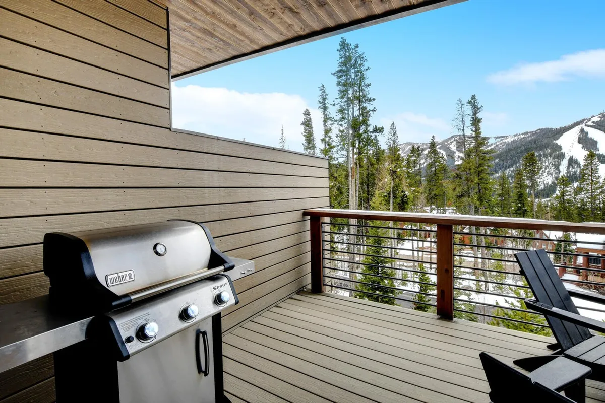 An expansive deck with a barbecue grill and ample seating, all overlooking a panoramic view of the mountains. The inviting setup is ideal for outdoor dining, morning coffee, or relaxing while taking in the spectacular landscape.