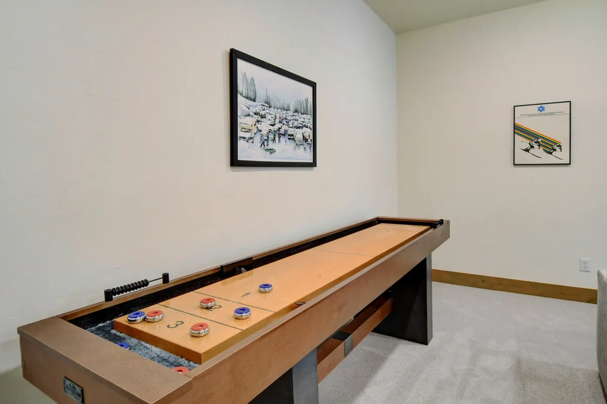 A shuffleboard table anchors this game zone, complemented by wall art and various game accessories, creating an inviting spot for friendly competition and fun gatherings.