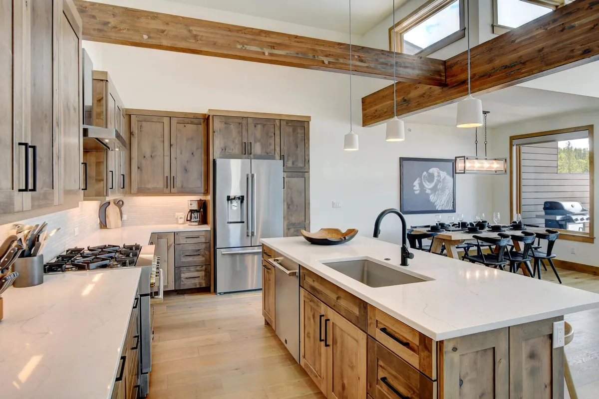 A spacious kitchen with a granite-topped island, sleek stainless steel appliances, wooden cabinetry, and a view into the adjacent dining area. The open layout encourages social interaction and seamless flow between spaces.